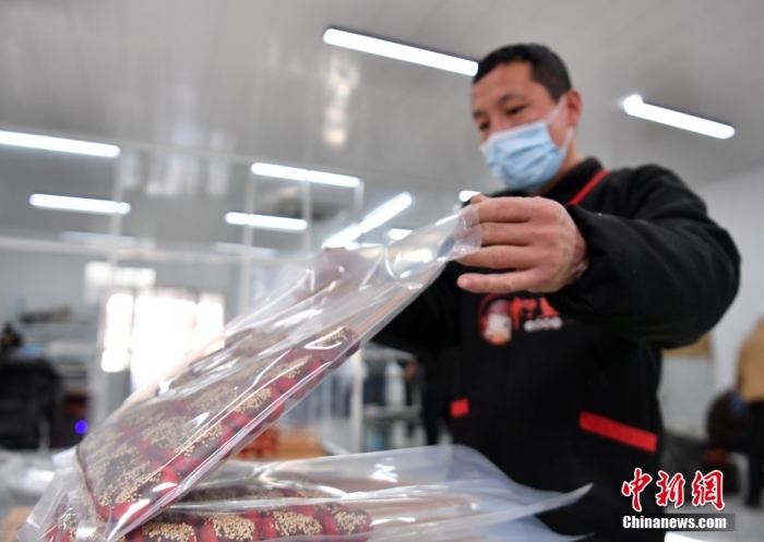 1月18日，雄安新區(qū)大樹(shù)劉莊村辛愛(ài)青家中的冰糖葫蘆加工廠，工人正對(duì)冰糖葫蘆半成品進(jìn)行真空塑封。作為遠(yuǎn)近聞名的“冰糖葫蘆村”，大樹(shù)劉莊村制作冰糖葫蘆的歷史已有100多年，全村三分之二的村民都會(huì)這門手藝，吸引不少游客慕名而來(lái)。 中新社記者 韓冰 攝